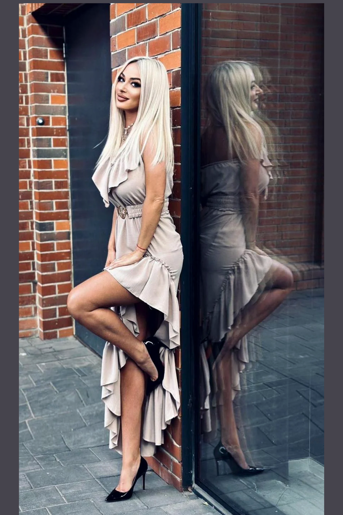 Abito beige corto davanti e lungo dietro di Moda-Mania con cintura elasticizzata e dettagli di volants, stile elegante e femminile.