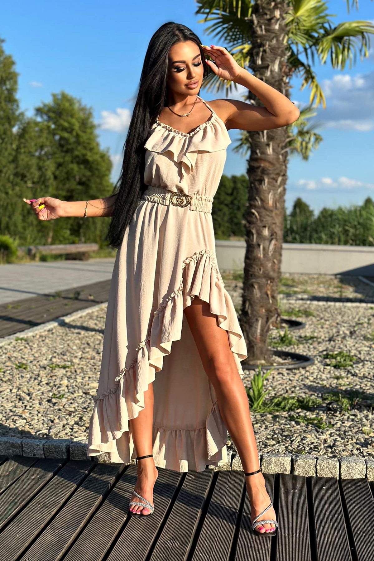 Abito corto beige chiaro Moda-Mania con gonna lunga dietro, cintura elasticizzata e dettagli di volants, stile elegante e femminile.