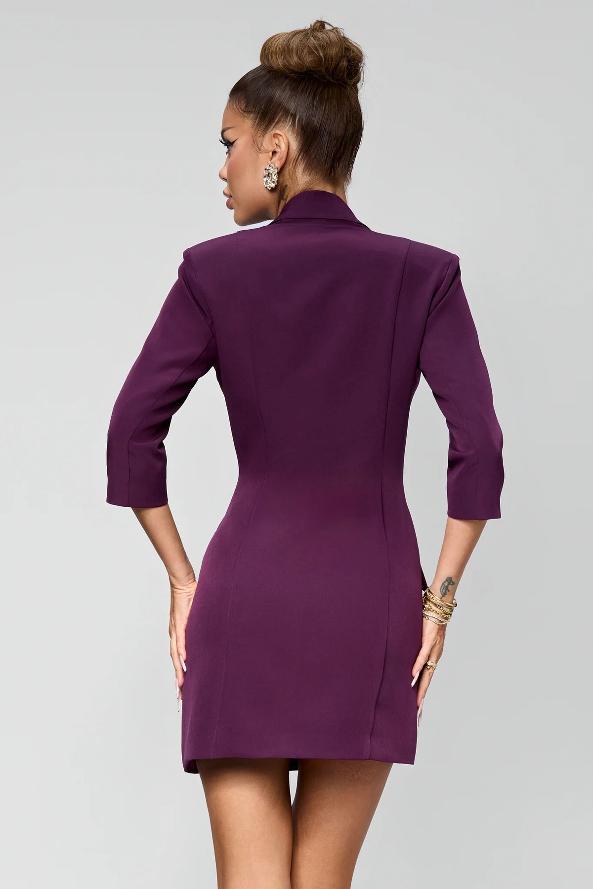 Abito blazer corto viola prugna Bby con catenelle e bottoni dorati, elegante e accessoriato, dettaglio del design e tessuto.