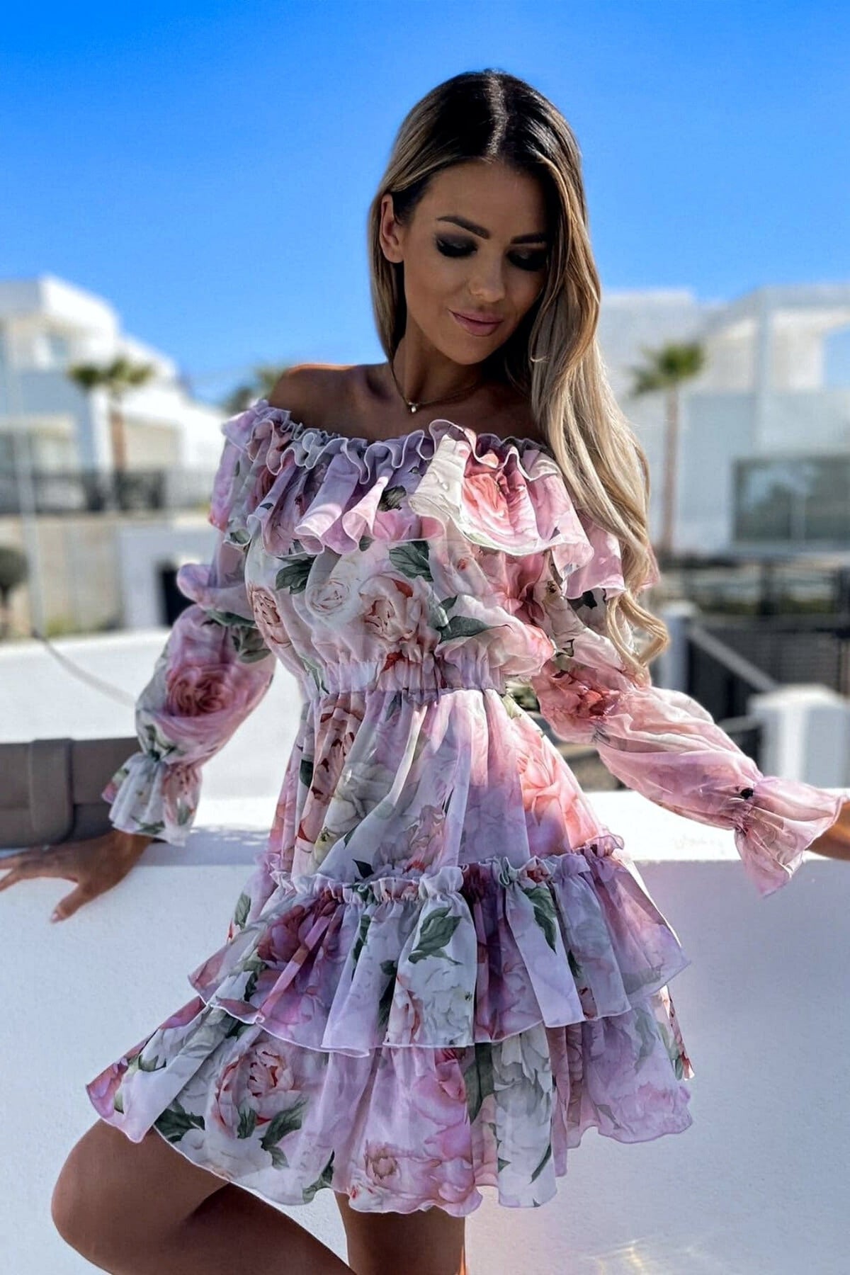 Abito corto svasato estivo Moda-Mania con fantasia floreale, scollo a barchetta e dettagli multi volants, ideale per la stagione calda.
