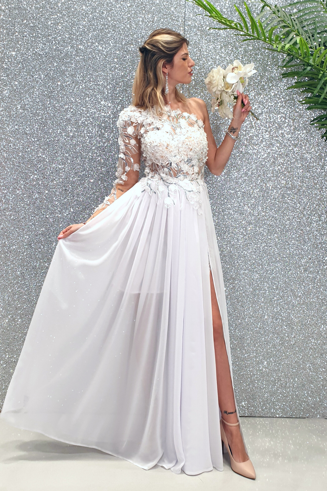 Abito lungo bianco con manica unica, strascico in georgette e corpetto a fiori 3D di Moda-Mania.