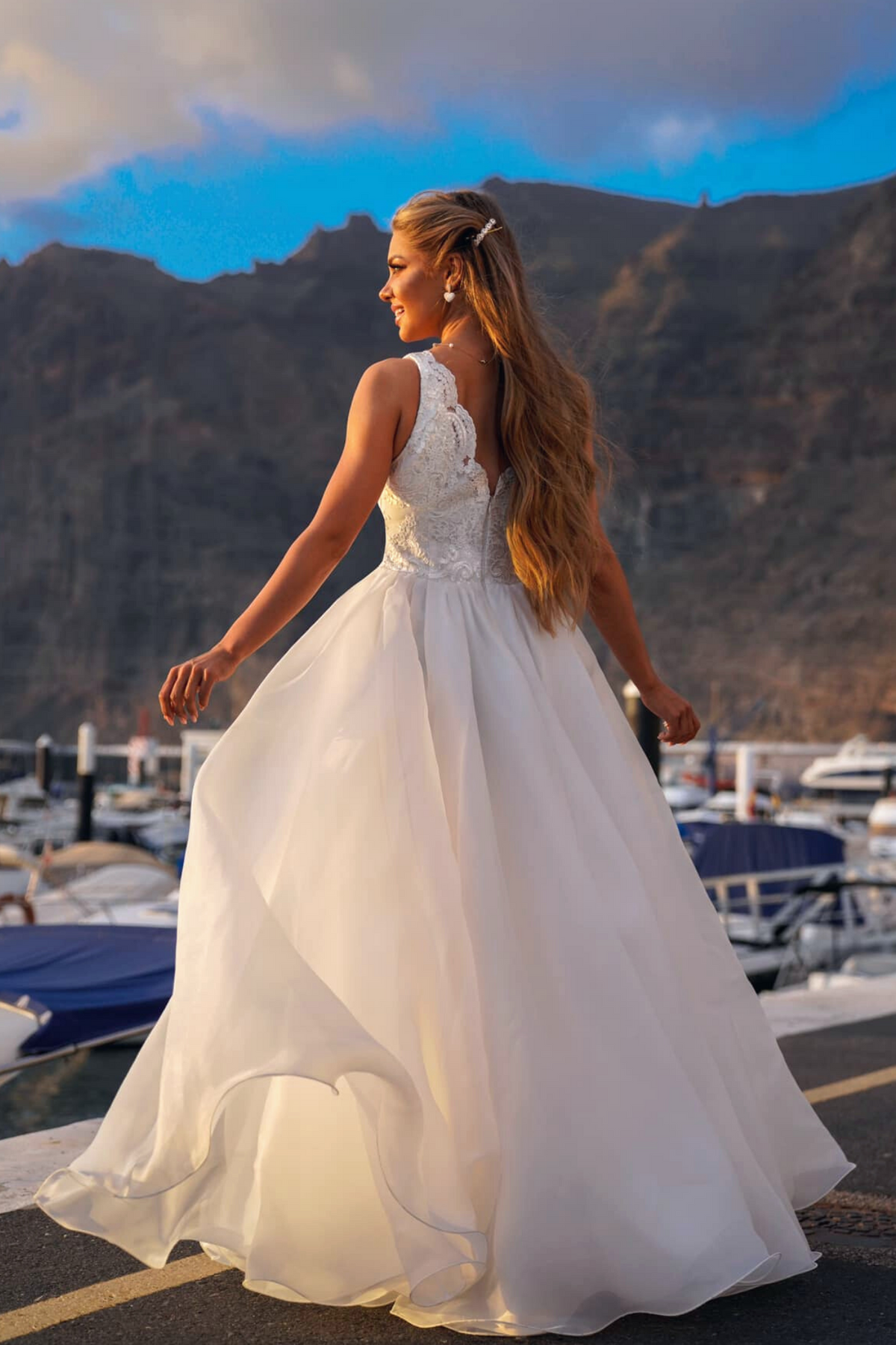 Abito lungo bianco da cerimonia Moda-Mania con corpetto ricamato e gonna ampia in organza su sfondo rosa cipria.