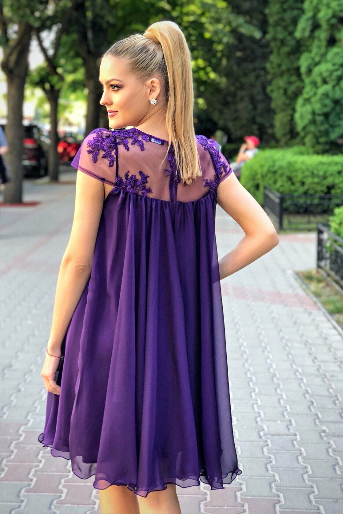 Abito svasato viola Artista in tessuto georgette con décolleté in tulle floreale, vestibilità elegante e dettagli raffinati.