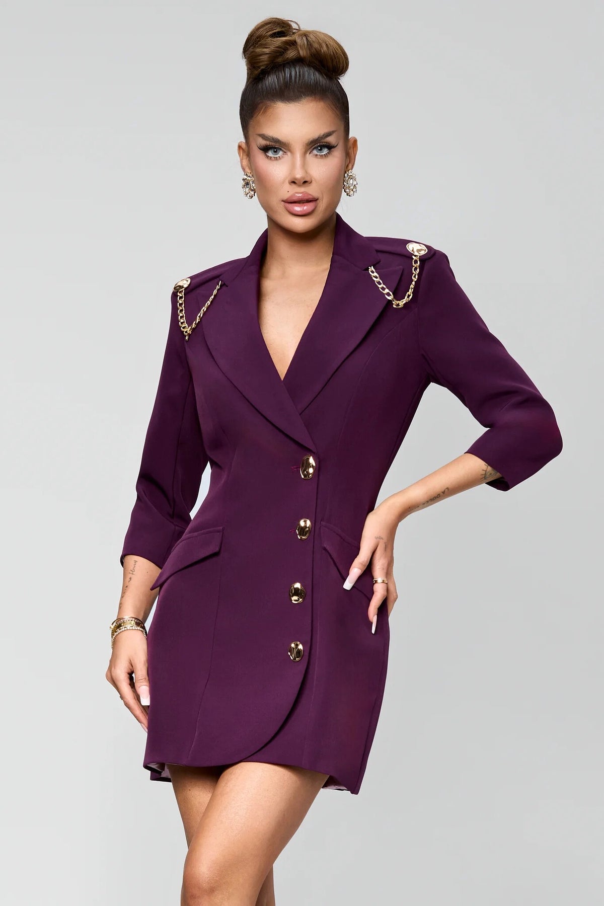 Abito blazer corto viola prugna Bby con catenelle e bottoni dorati, dettaglio di stile e accessori eleganti.
