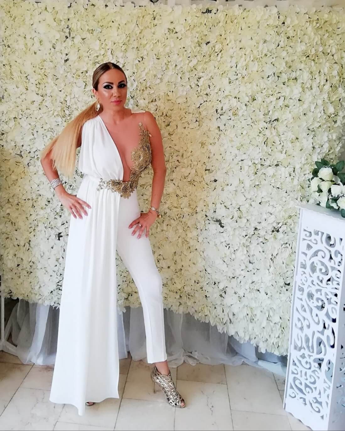 Salopette elegante bianca alla romana Bby con corpetto in tulle a fiori dorati e strascico laterale, abbigliamento da sera femminile.