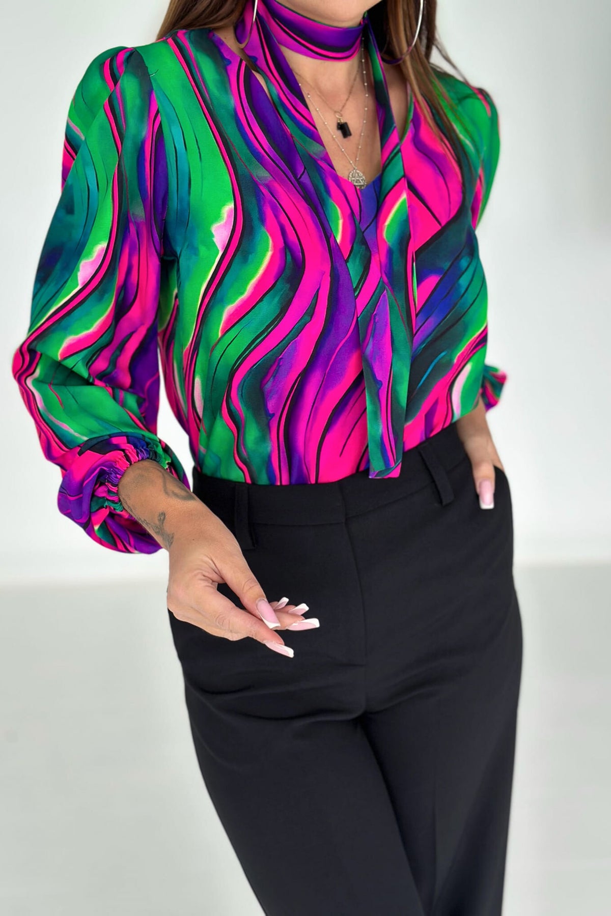 Blusa Moda-Mania a stampa multicolore verde, fucsia e viola con scollo a V e nastro in tessuto rimovibile.