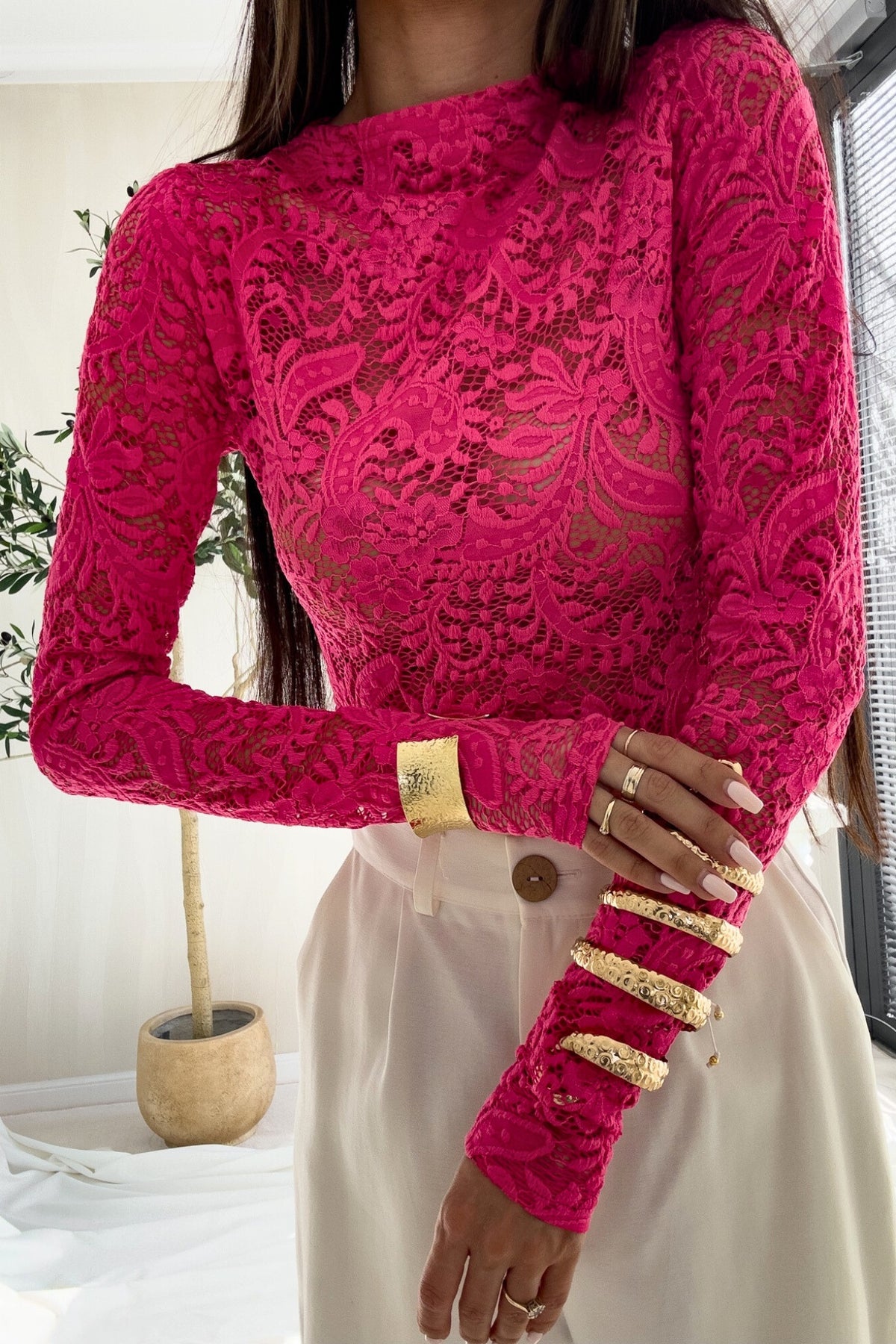 Blusa aderente fucsia in pizzo elasticizzato con maniche lunghe e fantasia floreale, firma Moda-Mania.