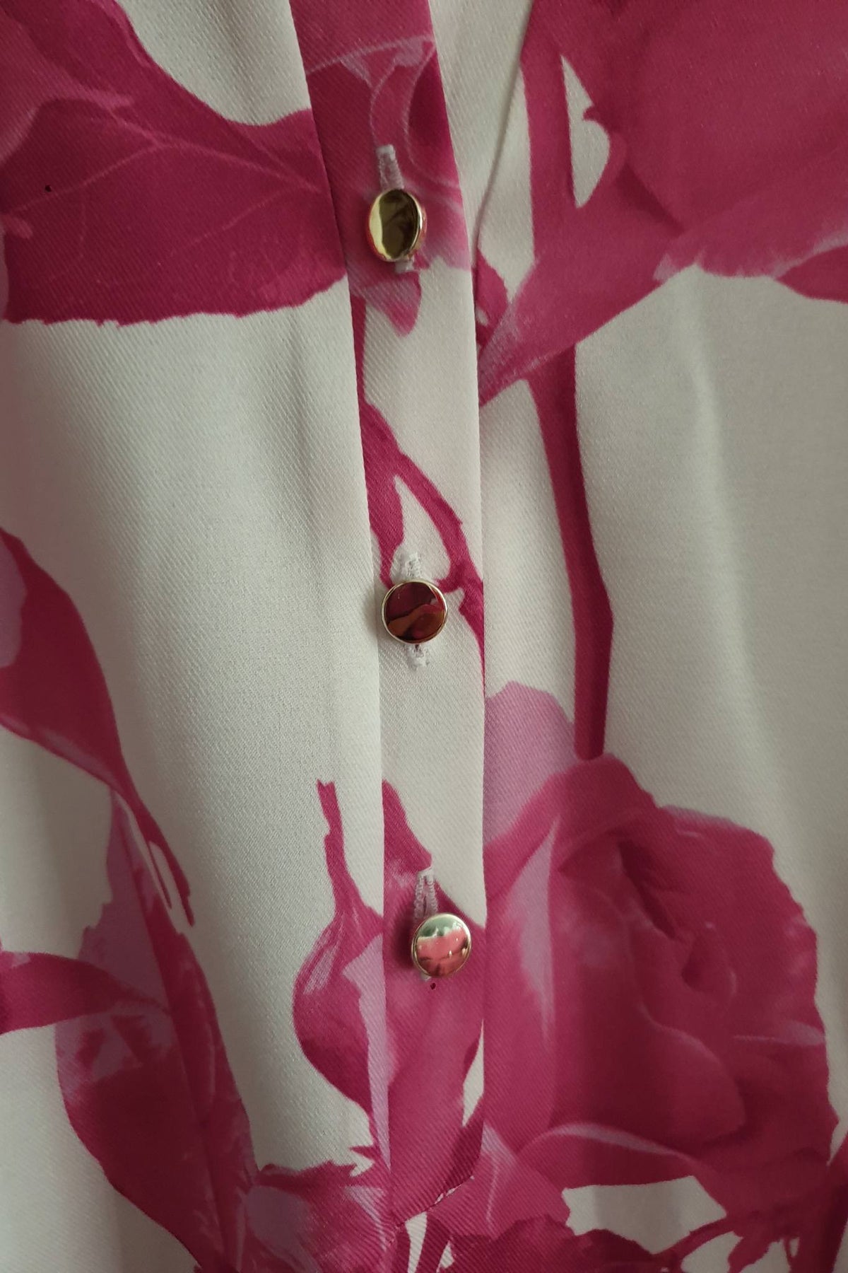 Blusa bianca floreale fucsia Moda-Mania con maniche tre quarti e bottoni dorati, tessuto leggero e stile femminile.