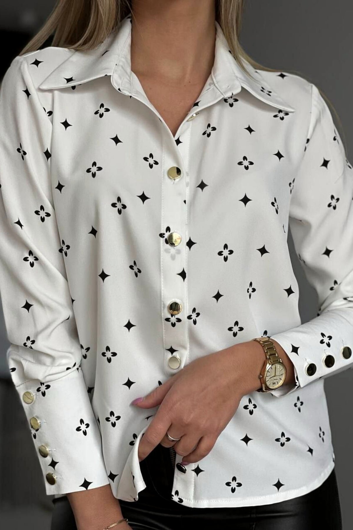 Camicia elegante bianca a fantasia nera con bottoni dorati, stile fashion, marca Moda-Mania, vista frontale.