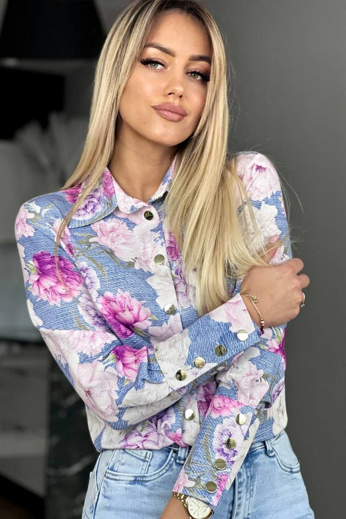 Camicia elegante bianca Moda-Mania con fantasia floreale rosa e bottoni dorati, tessuto leggero e dettagli raffinati.