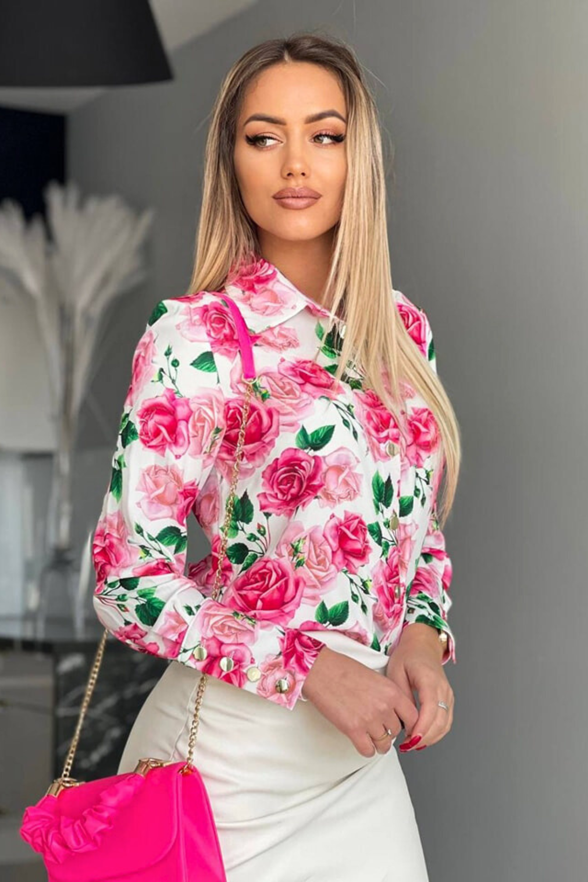 Camicia elegante bianca Moda-Mania con fantasia floreale rosa, bottoni dorati e dettagli raffinati, ideale per look sofisticato.