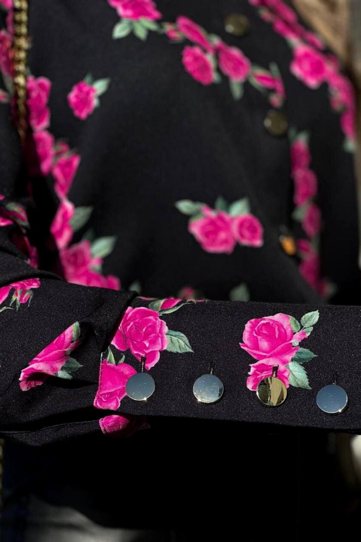 Camicia elegante nera Moda-Mania con fantasia di piccole rose fucsia e bottoni dorati, tessuto leggero e dettagli raffinati.