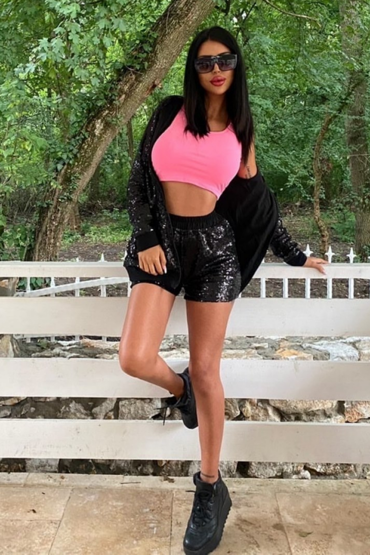 Completo a tre pezzi Foggi nero con paillettes e crop top rosa, visibile con pantaloni, giacca e top brillante e colorato.