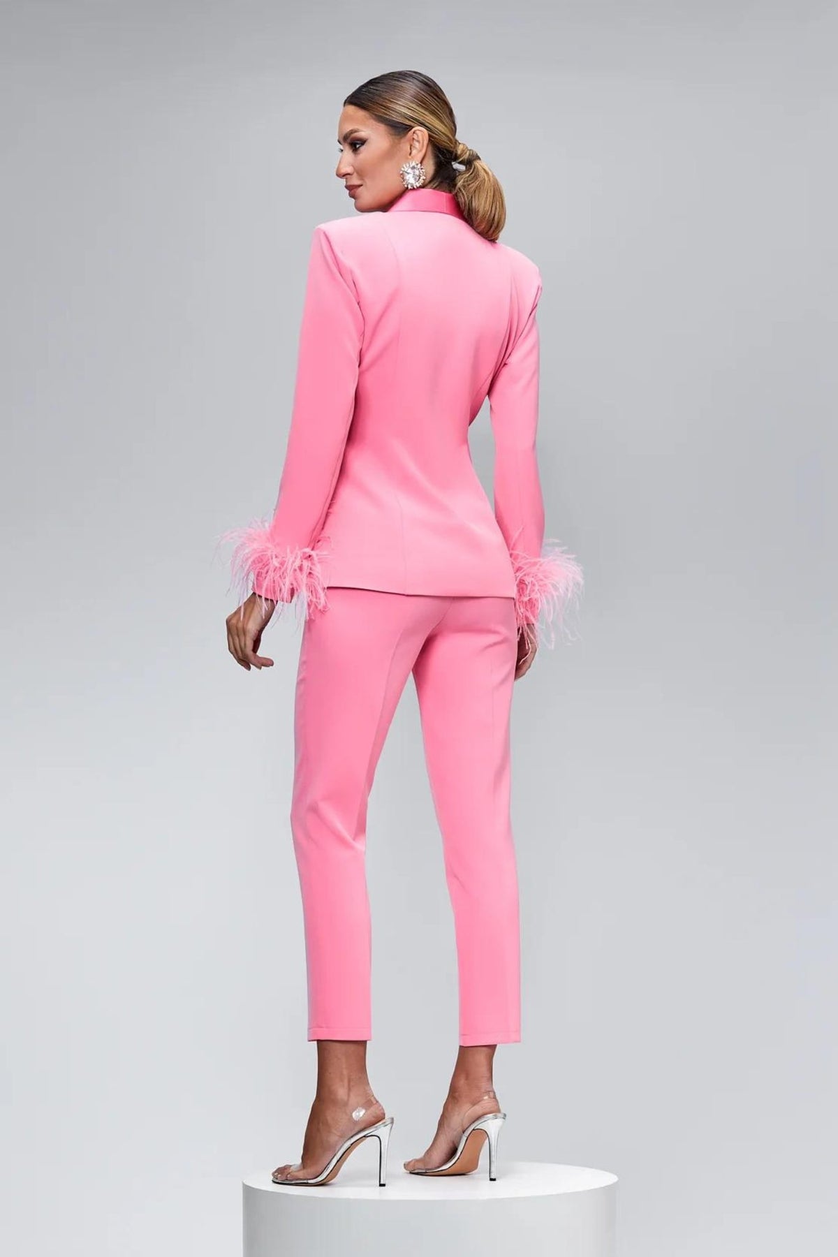 Completo tailleur rosa Bby con giacca accessoriata con piume e pantaloni a sigaretta, abbigliamento elegante e di moda.