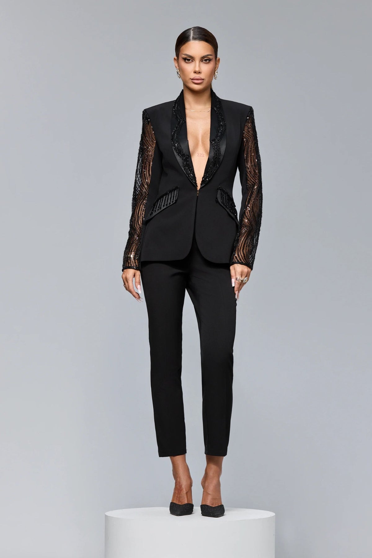 Completo tailleur nero Bby con giacca a maniche lunghe in tulle, decorazioni in paillettes, perline e pantaloni a sigaretta.