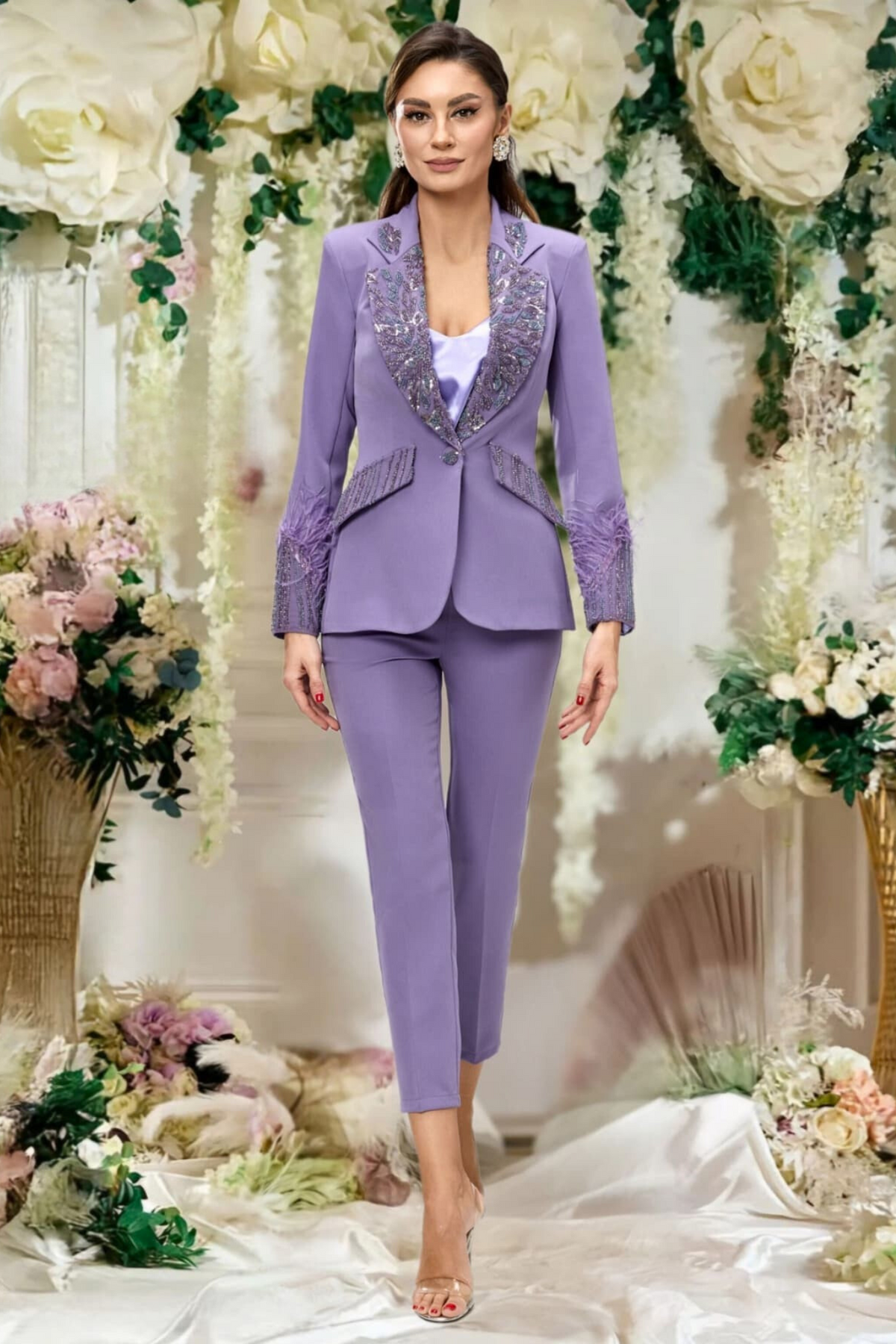 Completo tailleur Bby con giacca lilla impreziosita da piume e ricami in perline, pantaloni a sigaretta eleganti.