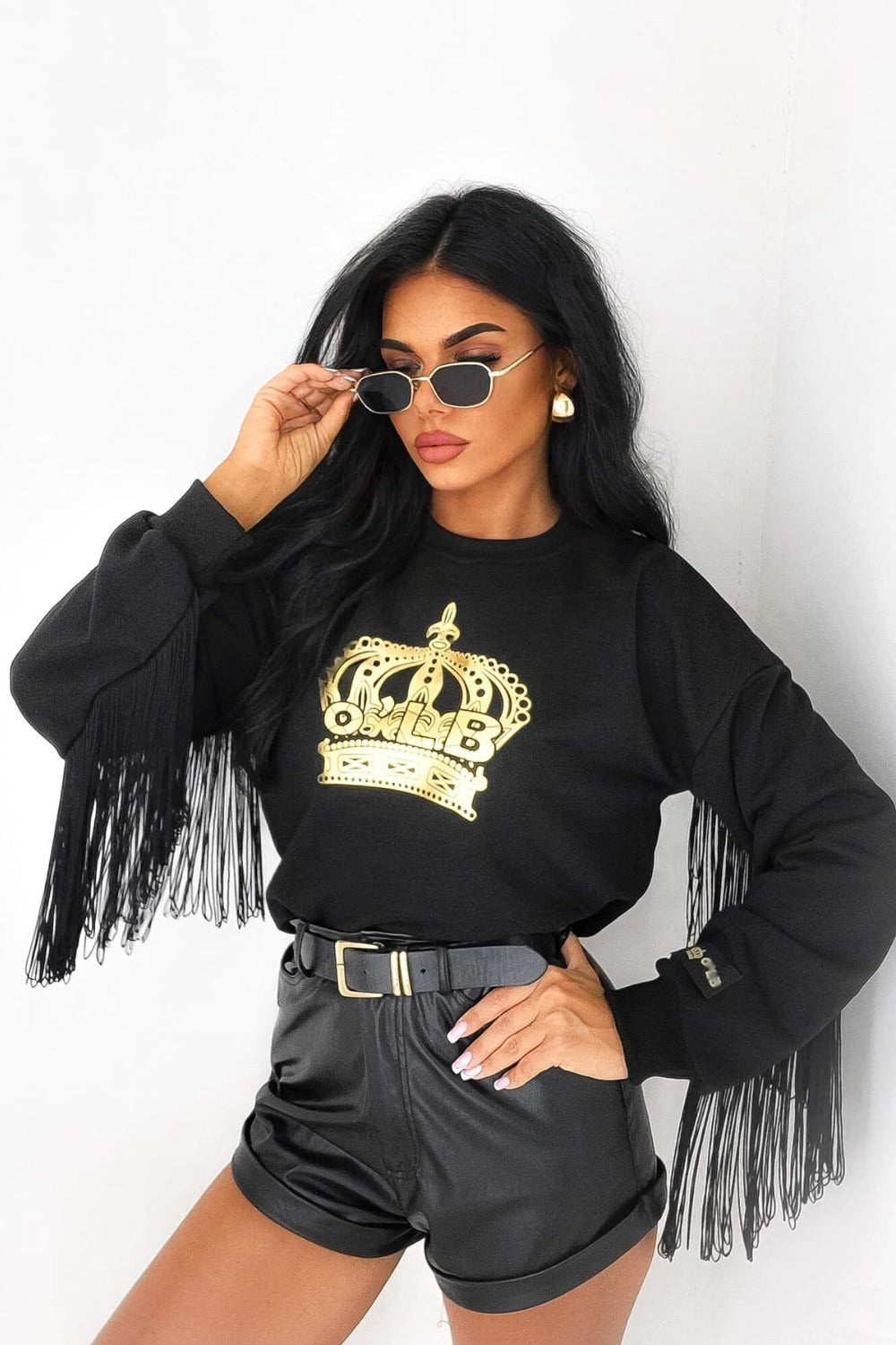 Maglia felpa nera casual di Moda-Mania con stampa dorata, logo corona, maniche lunghe e frange decorative nere, stile sportivo.