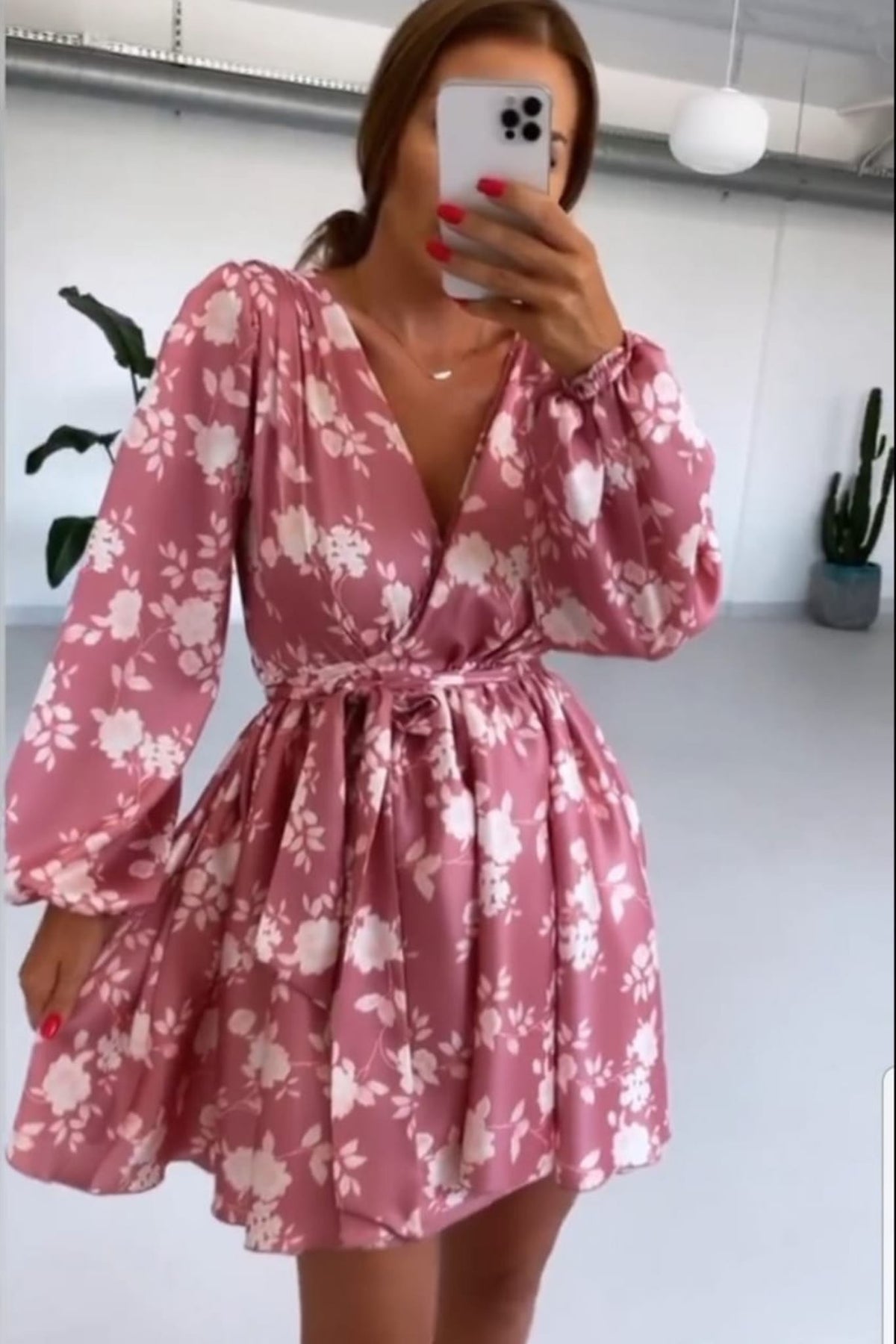 Abito estivo rosa floreale con maniche lunghe e gonna a ruota allacciabile in vita, firmato Moda-Mania, su modella in giardino