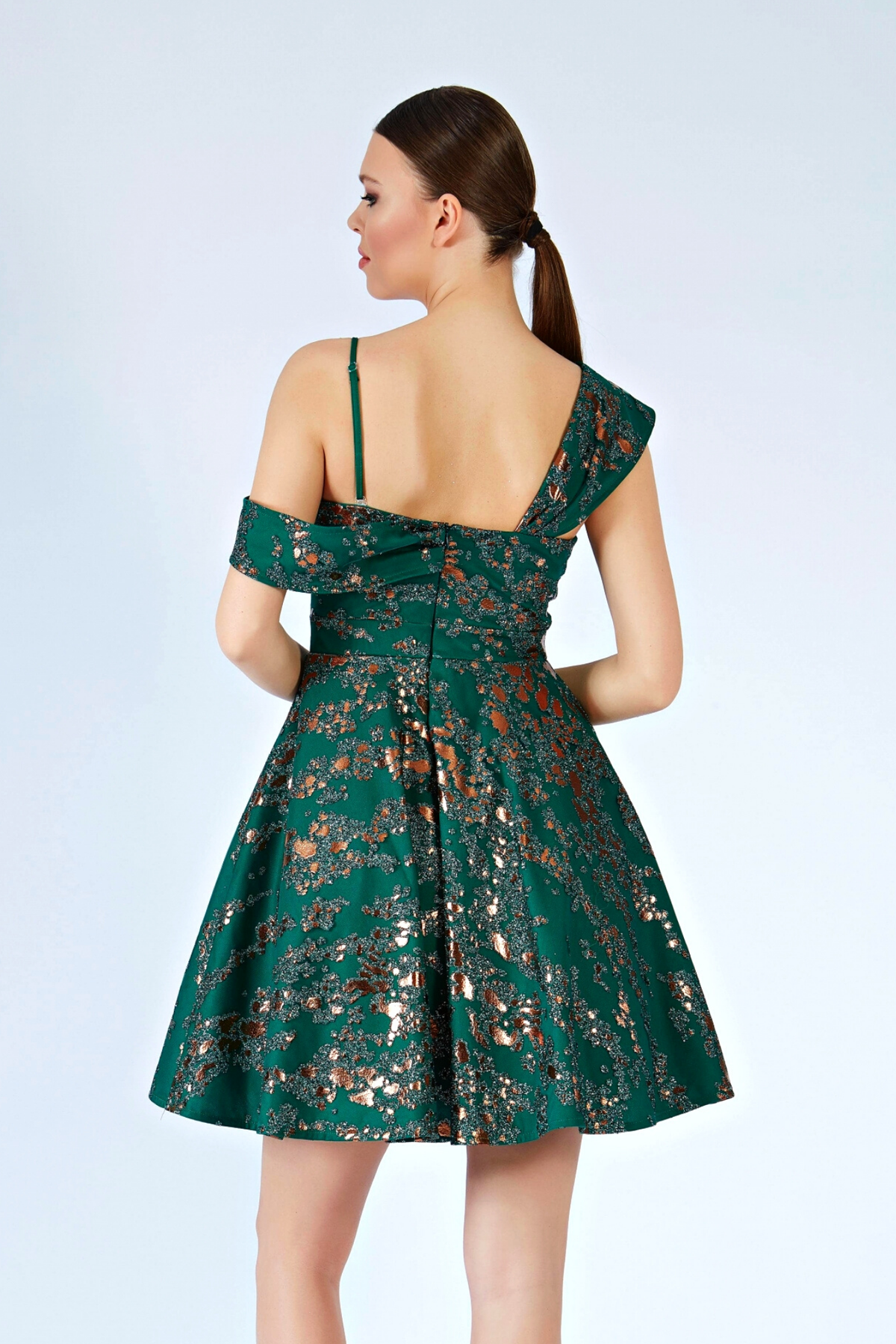 Abito corto svasato verde smeraldo con fantasia glitterata e spalla cadente, firmato Moda-Mania, elegante e alla moda.