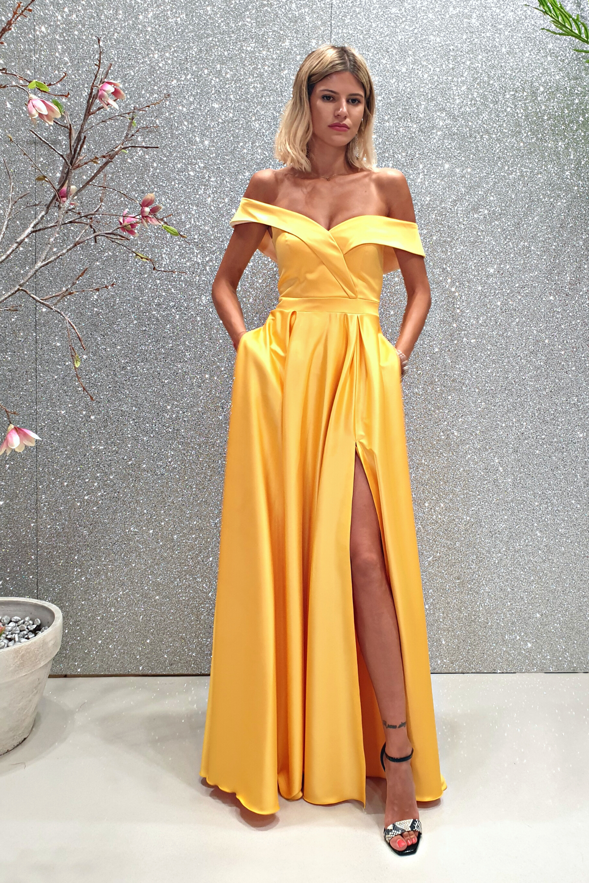 Abito lungo svasato giallo in taffetà con scollo a barchetta e spacco laterale, firmato Moda-Mania, visibile in dettaglio.