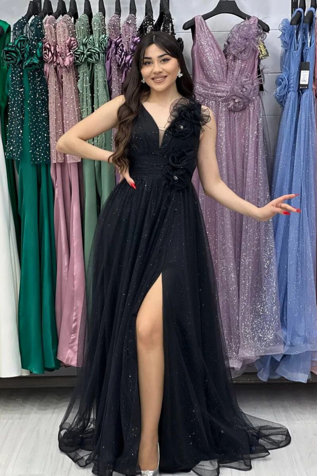 Abito lungo svasato nero in tulle glitterato con spacco e dettagli floreali, firmato Moda-Mania, visibile in primo piano.