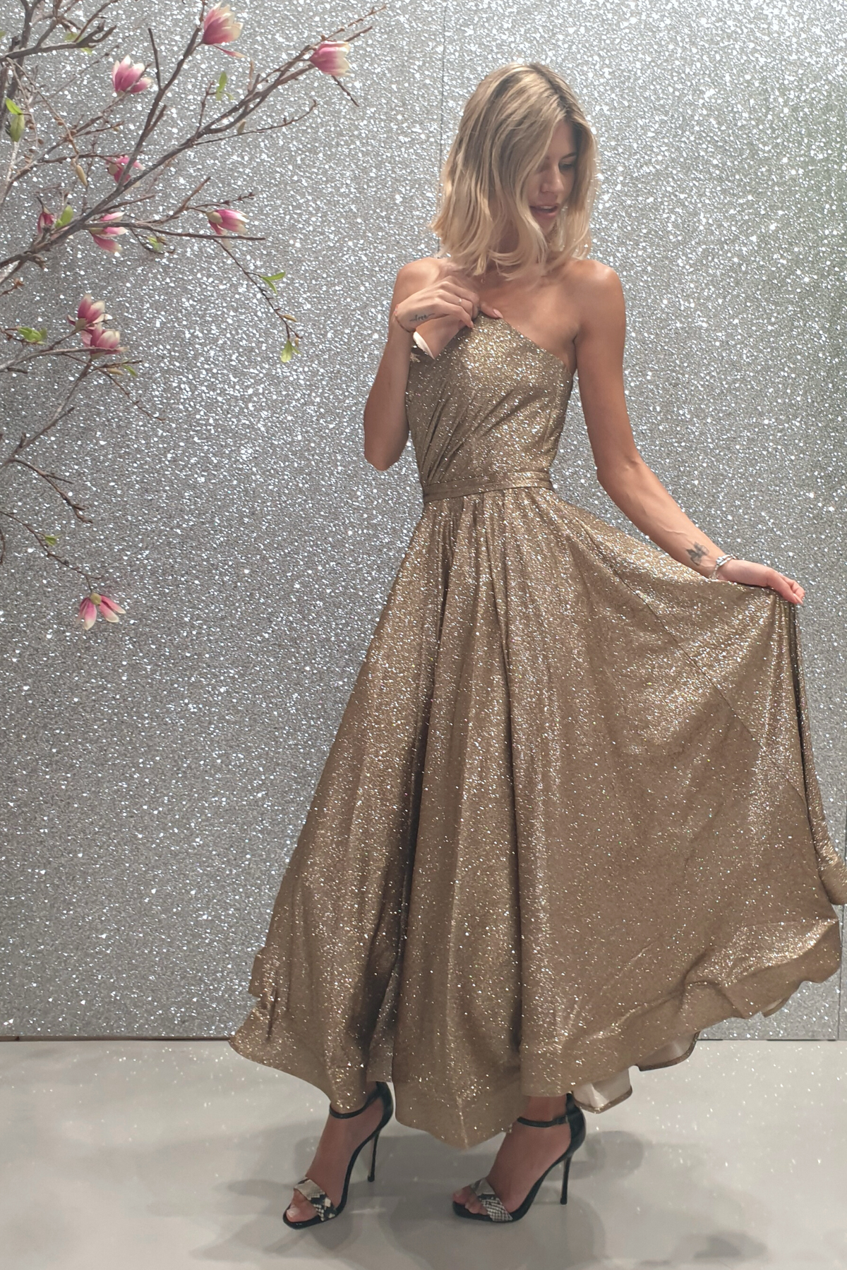 Abito lungo svasato in tessuto glitterato dorato bronzo con corpetto a cuore a punta e lunghezza asimmetrica, di Moda-Mania.