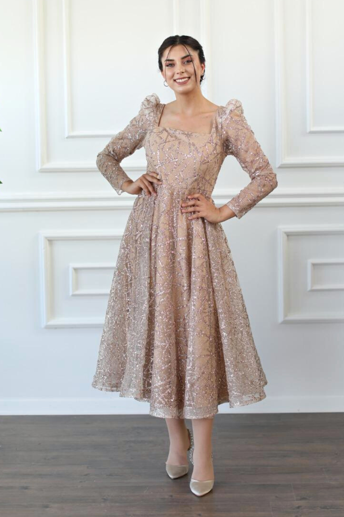 Abito lungo svasato in tulle con trama glitterata dorata a manica lunga, firma Moda-Mania, visibile dettaglio del tessuto e design elegante.
