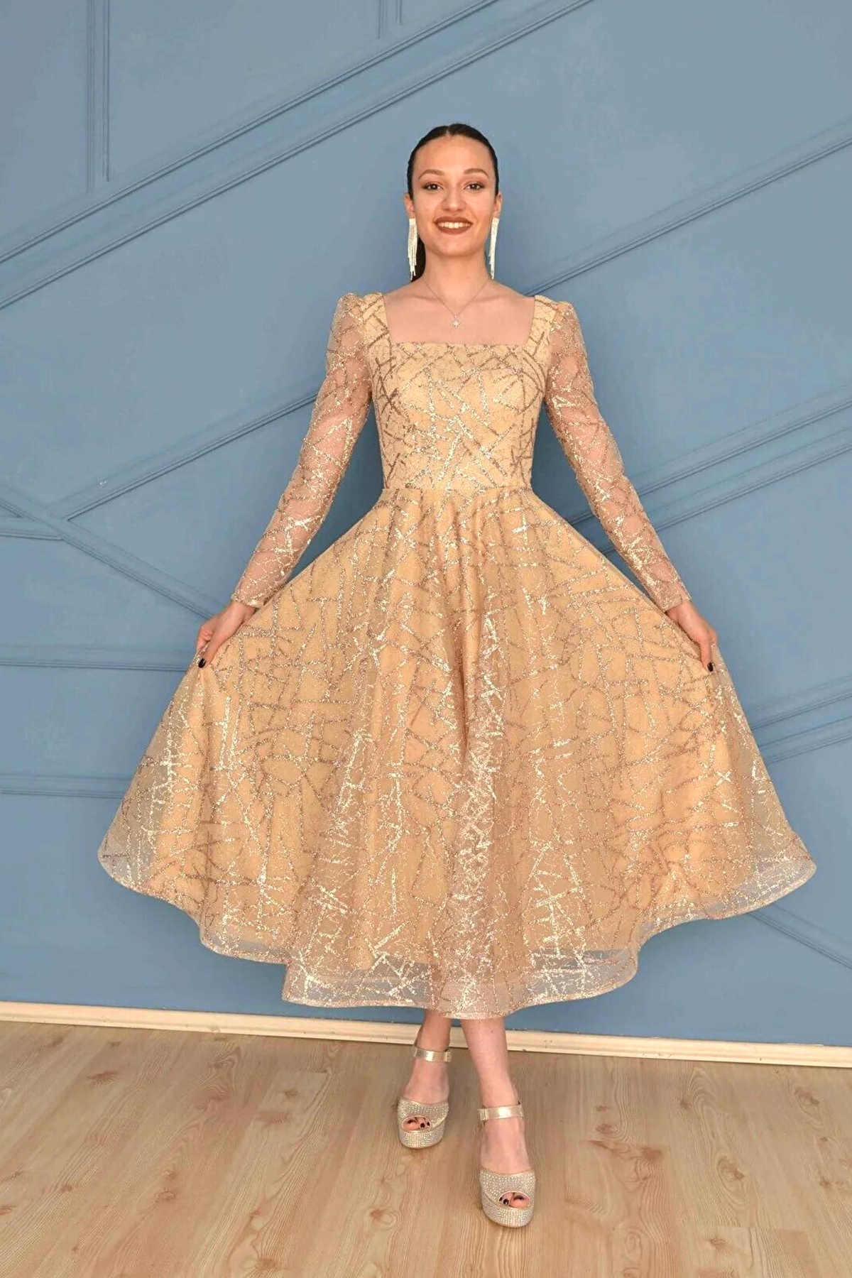 Abito svasato midi in tulle con trama glitterata dorata e maniche lunghe, firmato Moda-Mania, elegante e raffinato.