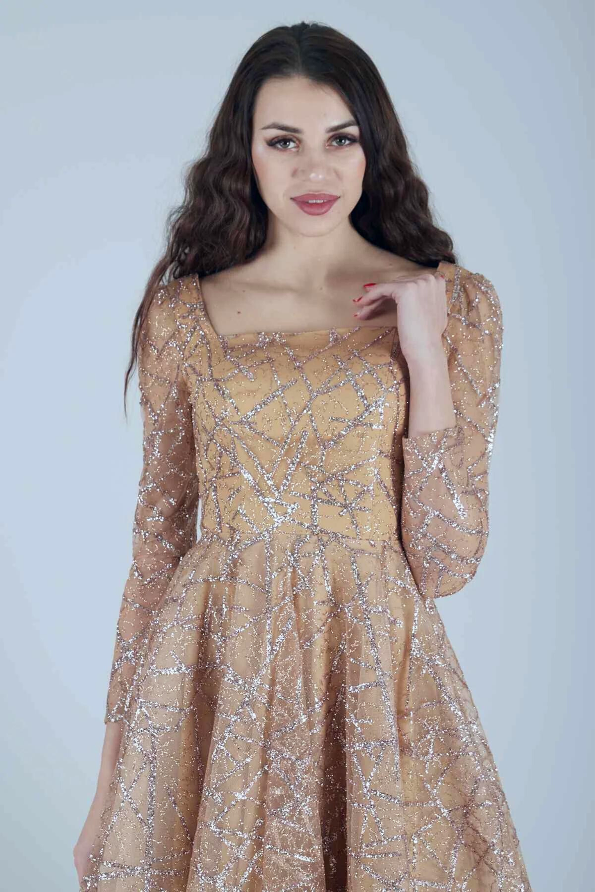 Abito lungo svasato in tulle con trama glitterata dorata e maniche lunghe, firmato Moda-Mania.
