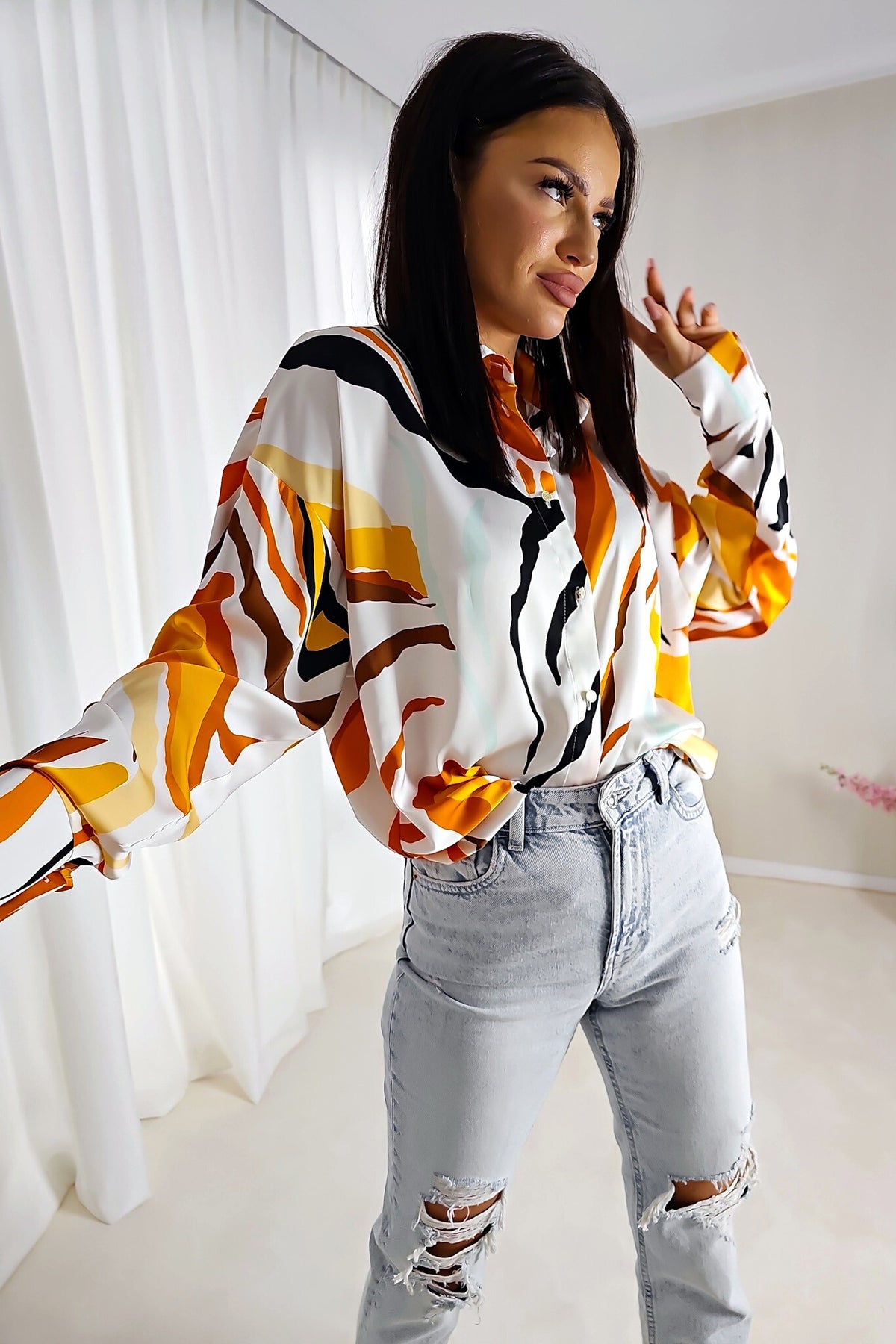 Camicia bianca larga con fantasia astratta arancione, giallo e nero in tessuto satinato lucido con bottoni dorati, marca Moda-Mania.