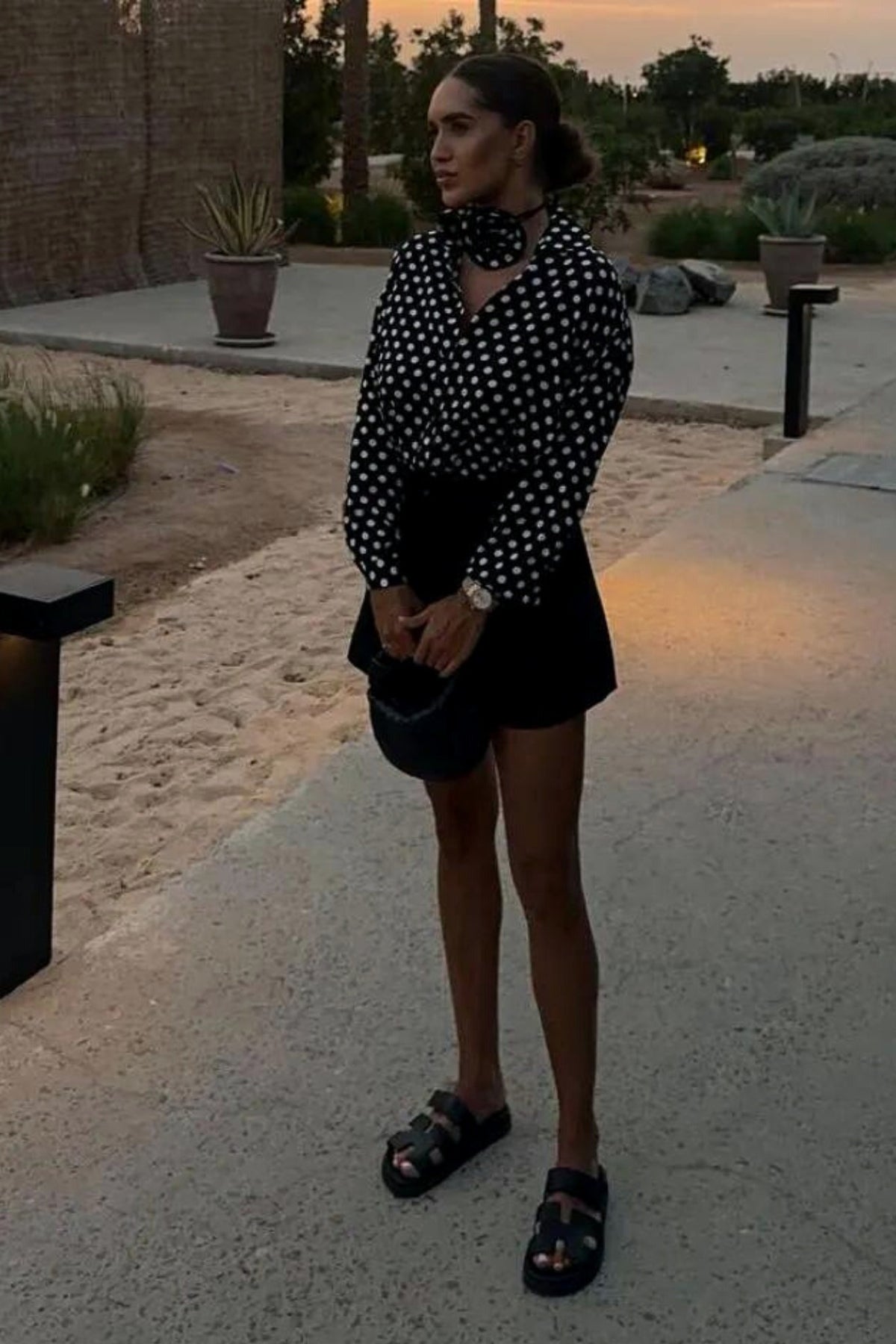 Camicia nera a pois bianchi in viscosa di Moda-Mania, con fiore in tessuto come dettaglio decorativo.