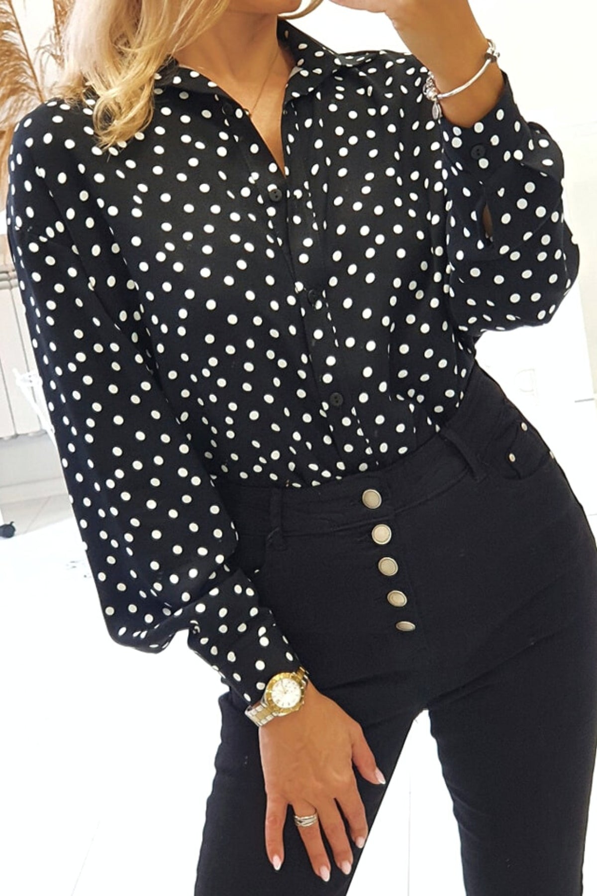 Camicia nera in viscosa con pois bianchi, accessoriata con fiore in tessuto, stile casual e femminile.