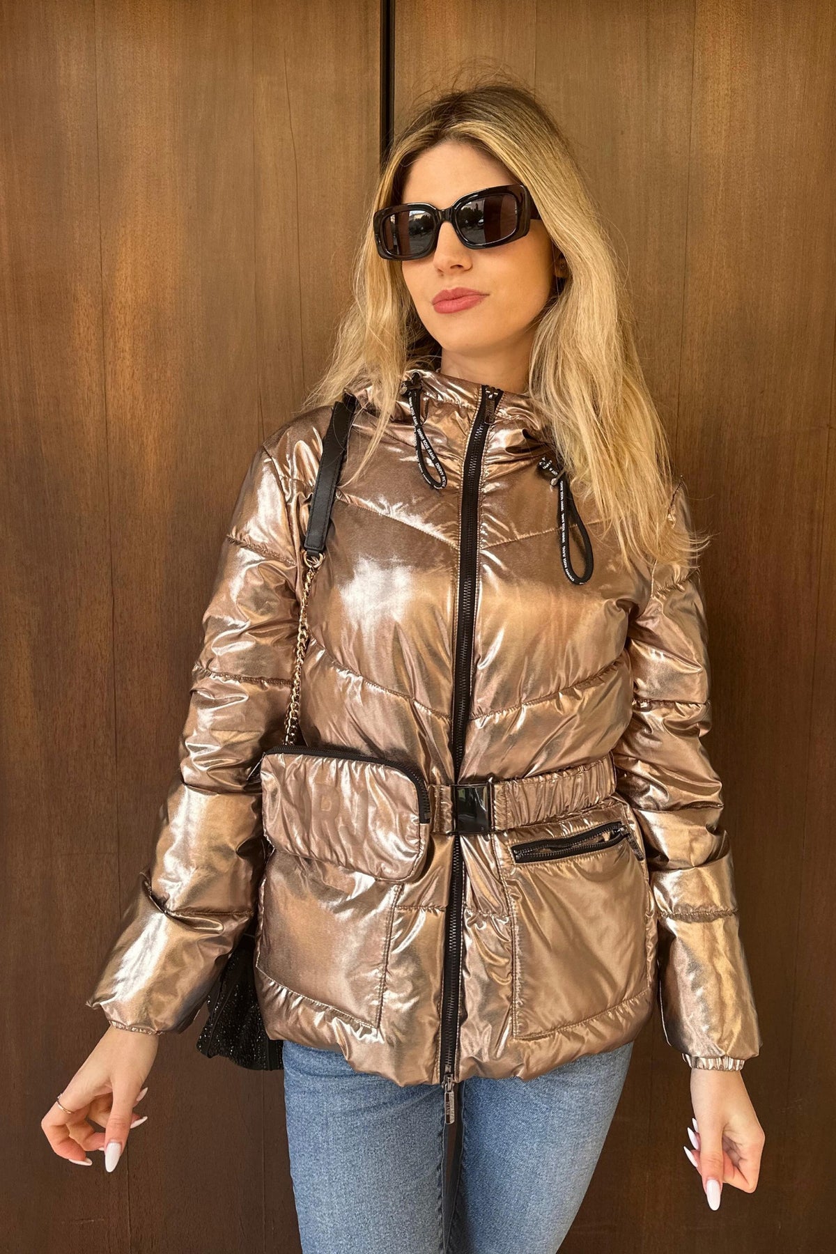 Giacca invernale Denny Rose bronzo laminato con cappuccio e cintura, dettaglio portafoglio, stile elegante e moderno.
