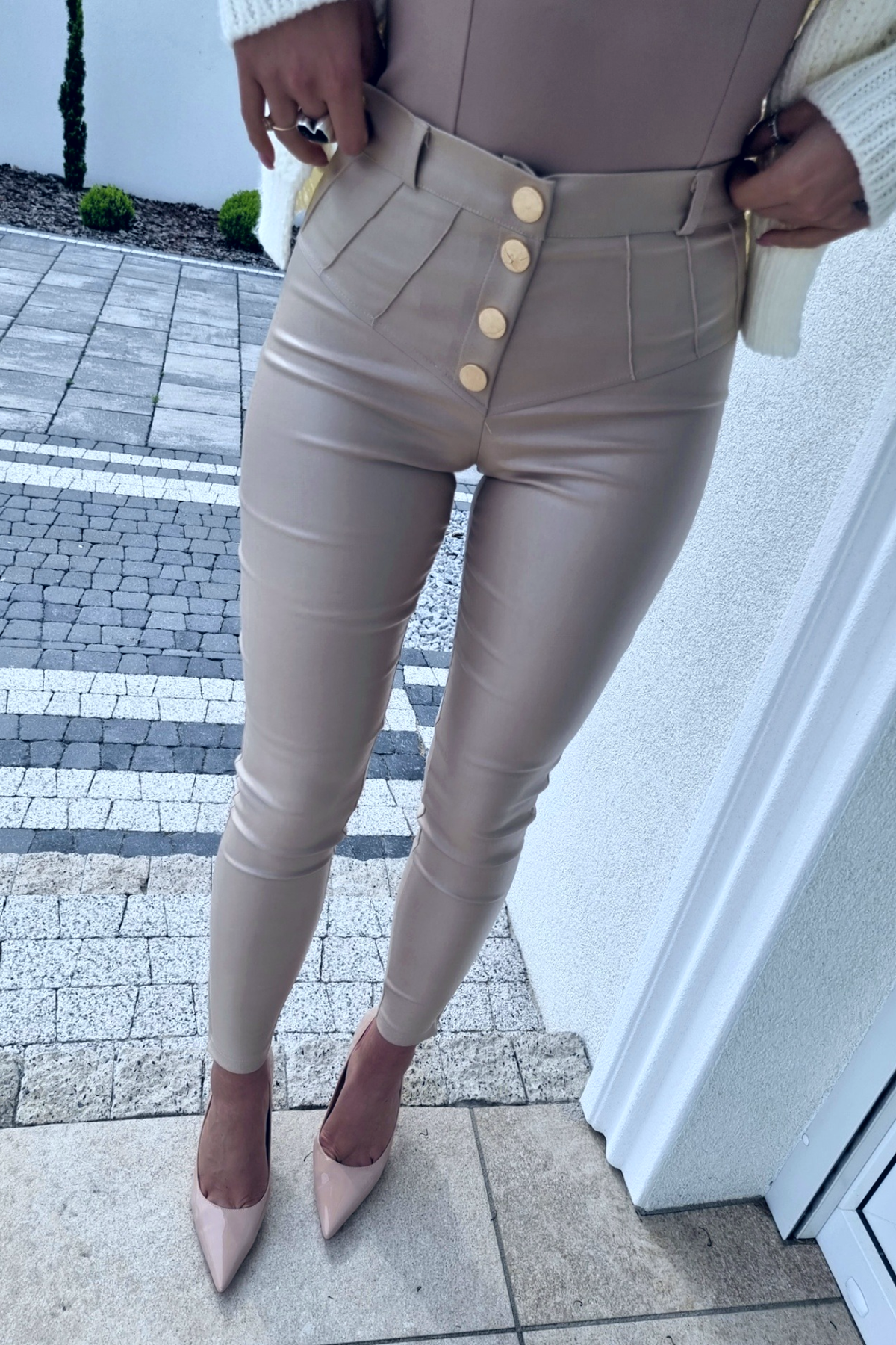Pantaloni beige in similpelle moda-mania a vita alta con bottoni e cerniere, dettagli fashion e stile elegante.