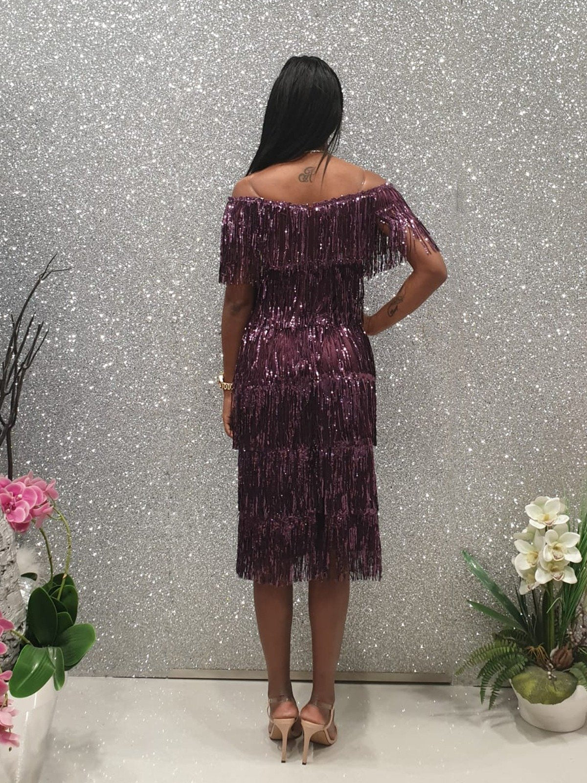Abito corto viola Moda Mania con frange decorative in paillettes e scollo a barchetta, dettaglio laterale e tessuto lucido.