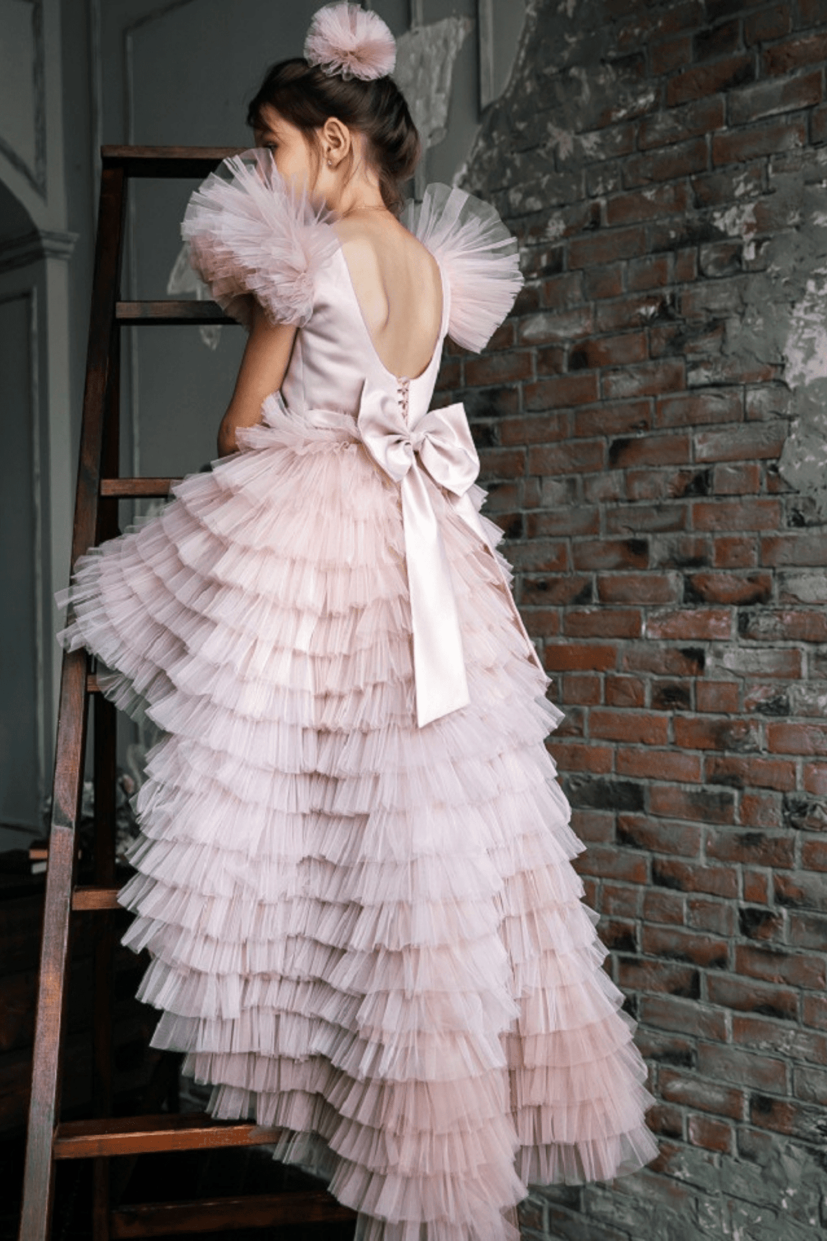 Abito rosa per bimba Moda-Mania con maniche a ventaglio, gonna in tulle multi volants e strascico staccabile.