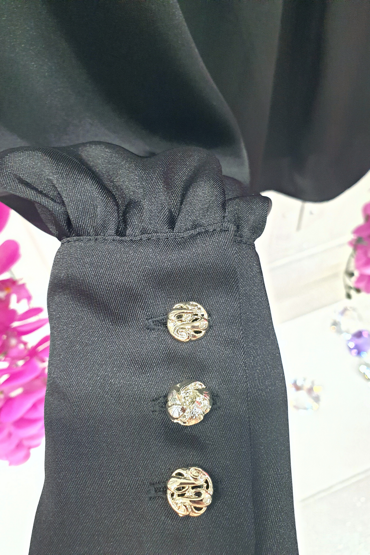 Camicia elegante nera in tessuto satinato di Moda-Mania con maniche a sbuffo e bottoni gioiello bianchi, dettaglio frontale.