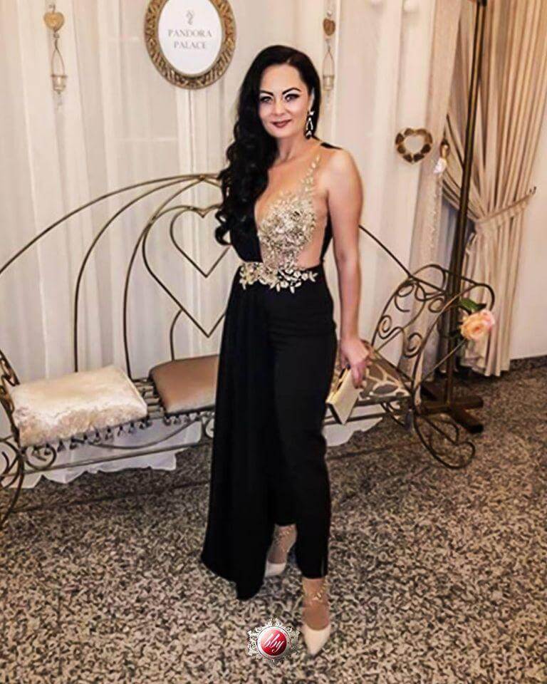 Salopette elegante nera Bby con corpetto in tulle dorato a fiori e strascico laterale, abbigliamento femminile raffinato.