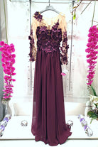 Abito lungo viola prugna Moda-Mania con corpetto in tulle nude a fiori 3D e strascico elegante, dettaglio visibile nell'immagine.