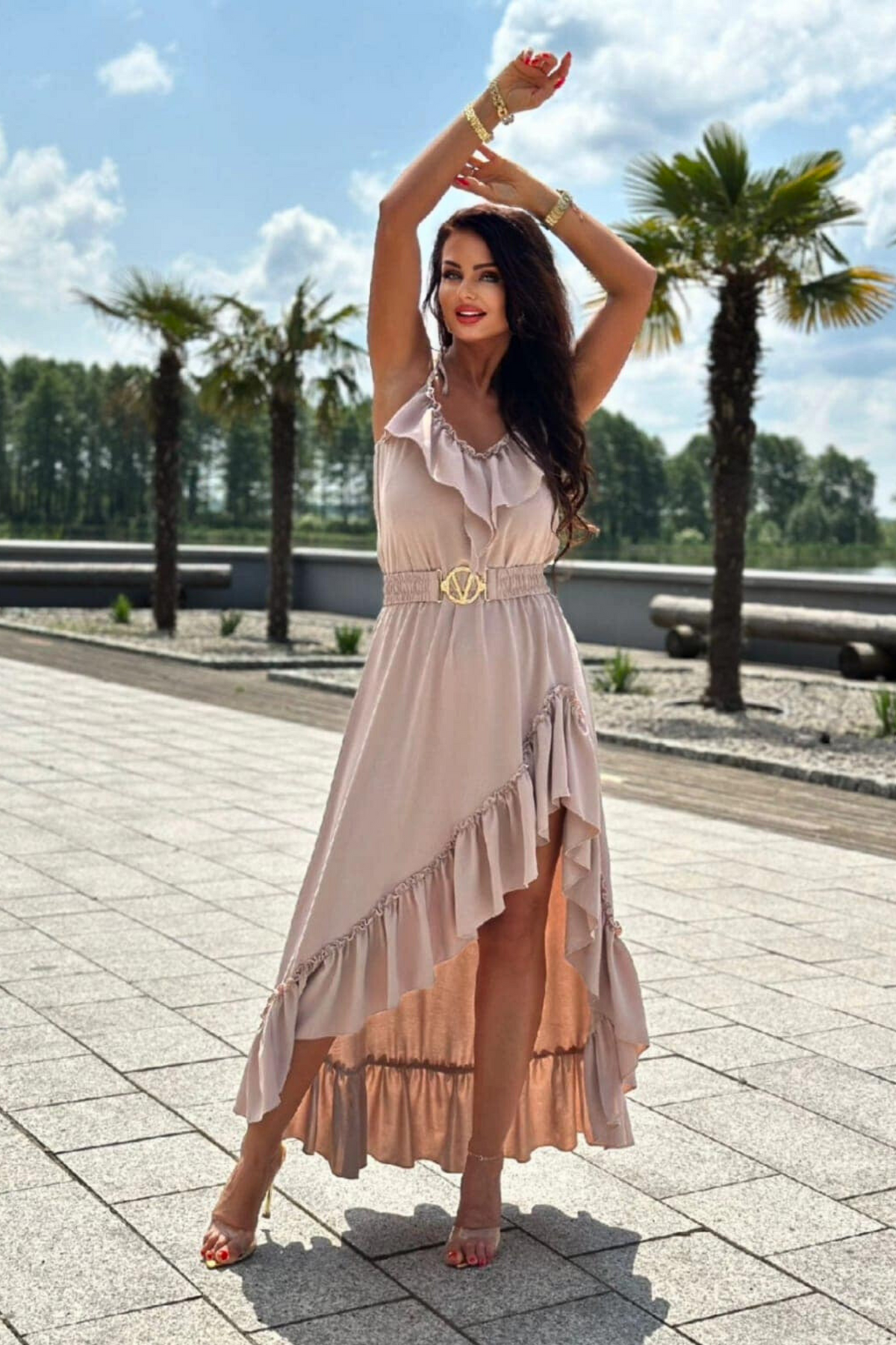 Abito corto beige chiaro Moda-Mania con gonna lunga dietro, cintura elasticizzata e volant, stile elegante e femminile.