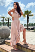 Abito corto beige chiaro Moda-Mania con dettagli volant, cintura elasticizzata e gonna lunga dietro, stile elegante e femminile.
