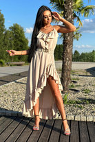 Abito corto beige chiaro Moda-Mania con gonna lunga dietro, cintura elasticizzata e dettagli di volants, stile elegante e femminile.