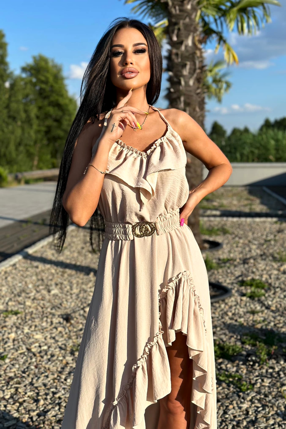 Abito corto beige chiaro Moda-Mania con gonna lunga dietro, cintura elastica e dettagli di volant, stile femminile e elegante.
