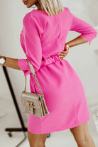 Abito casual fucsia Moda-Mania, linea dritta con cintura e fibbia dorata, tessuto leggero e dettagli eleganti.