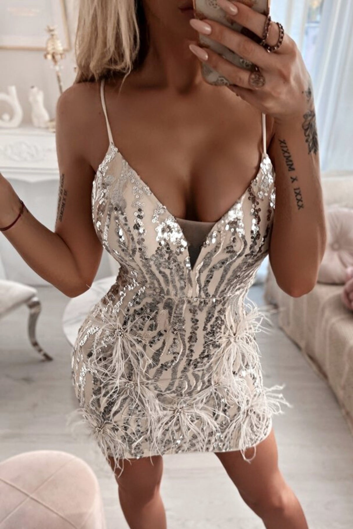 Abito corto aderente grigio caldo Moda-Mania con decorazioni in paillettes argento, piume e strass, dettagli eleganti e raffinati.