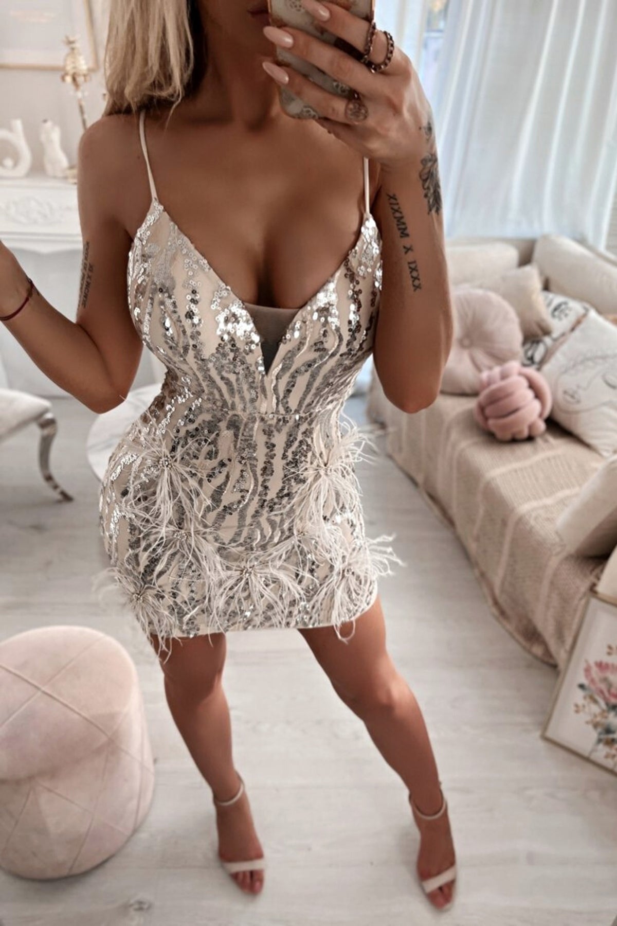 Abito corto aderente grigio caldo con paillettes argento, piume e strass, dettagli decorativi, firma Moda-Mania.