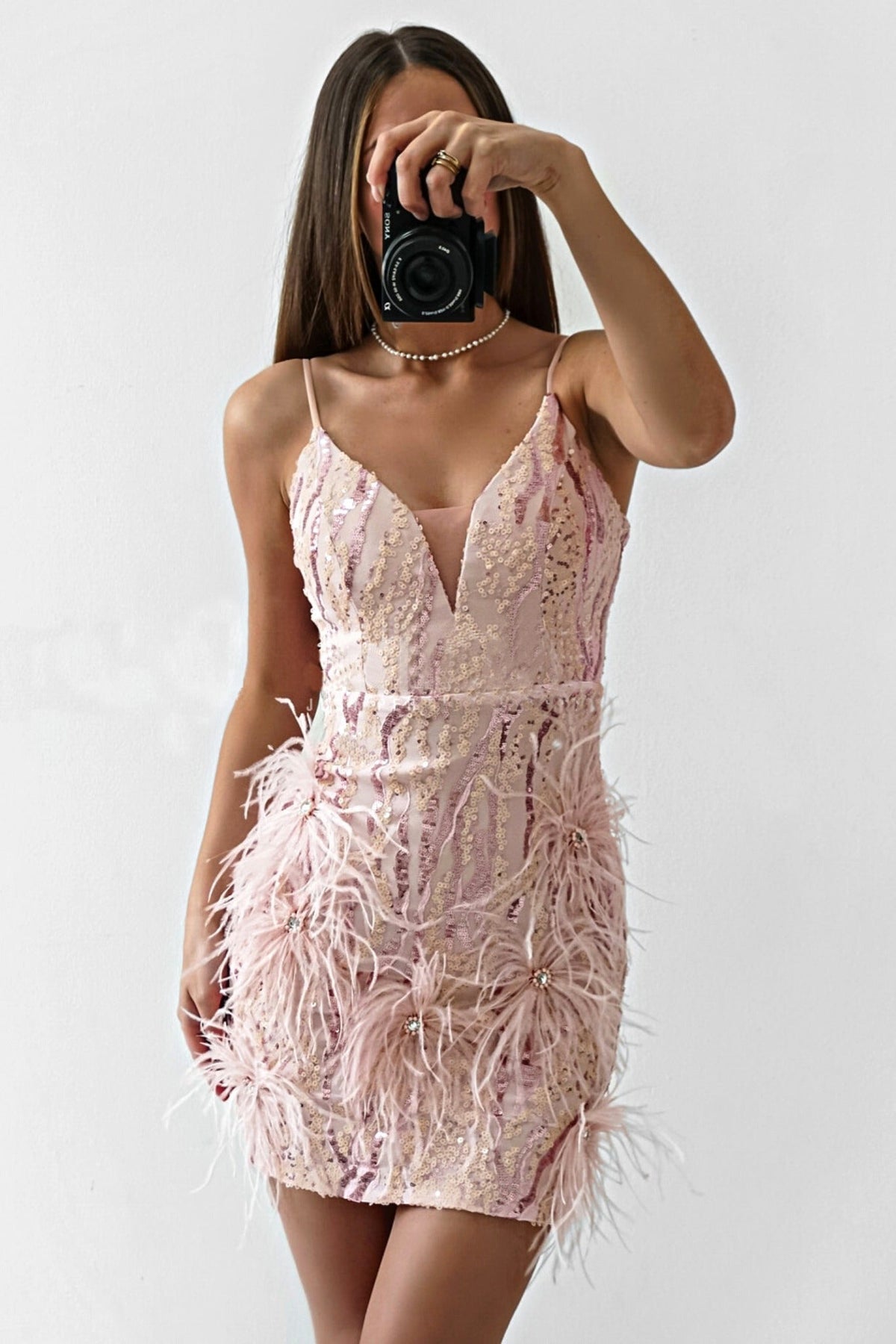 Abito corto aderente rosa Moda-Mania con decorazioni in paillettes, piume e strass, dettaglio visibile sul tessuto e decorazioni.