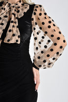 Abito corto nero in velluto con maniche in tulle nude a pois neri, vestibilità elegante e dettagli femminili di Moda-Mania.