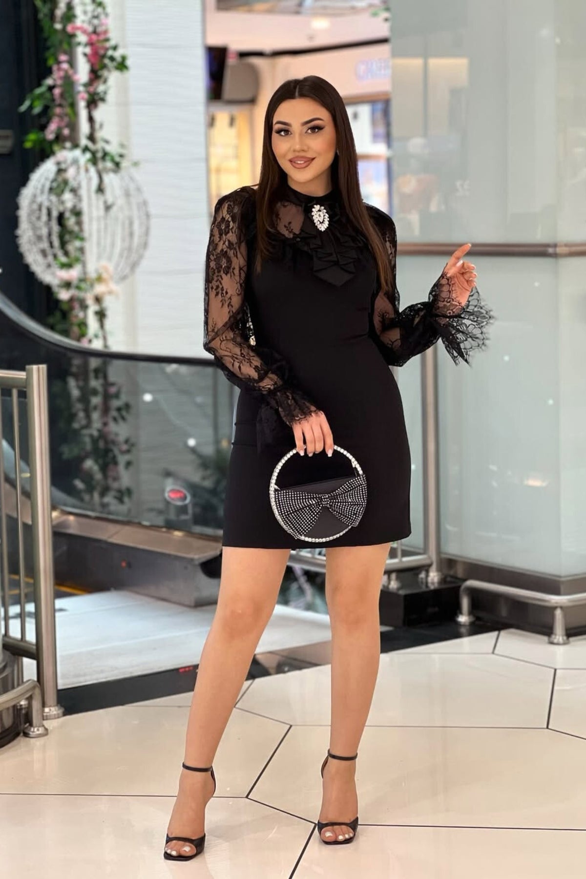 Abito corto nero in linea dritta con maniche in pizzo e spilla decorativa Jabout, moda Mania, dettaglio elegante e femminile.