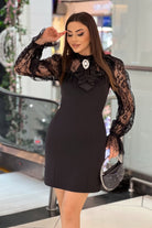 Abito corto nero linea dritta con maniche in pizzo e spilla decorativa, vestito elegante Moda-Mania, dettaglio in tessuto e accessori